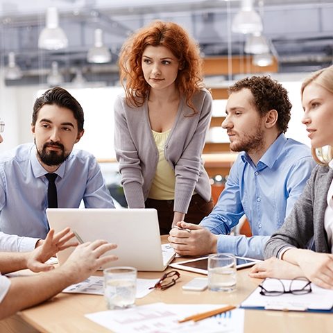 Group of business partners listening to colleague at meeting